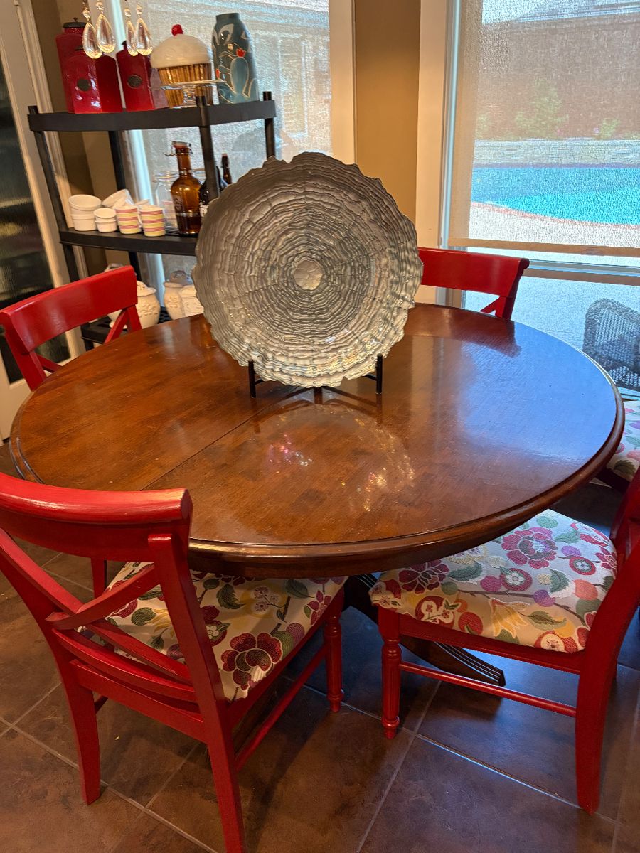 Solid wood round dining table with six chairs. The chairs are covered upholstered.