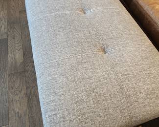 A large Grey Fabric Bench. 