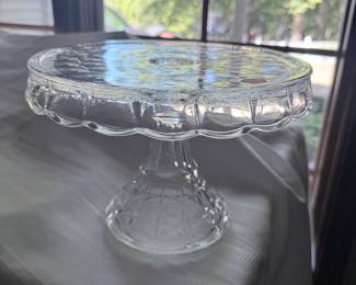 This is a vintage Indiana Glass "Constellation" pattern cake stand. It is a pressed glass pedestal cake stand with a "rum well" in the center of the plate. 
