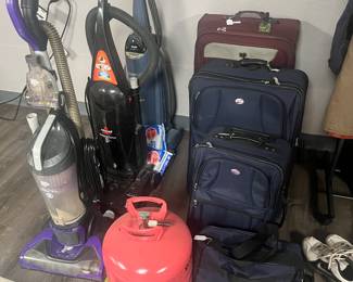 Assortment of vacuums and luggage 