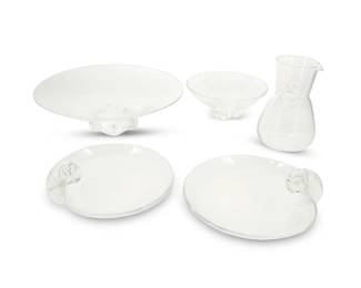 2052
A group of Steuben glass table items
Lat 20th century
Each with etched Steuben script mark
Comprising a footed shallow bowl (3.875" H x 12.375" Dia.), two snail scroll handle dishes (3" H x 8.625" Dia.), a thumbprint carafe/pitcher (7.25" H x 4.75" Dia.)., and a 'Floret' bowl (3.25" H x 7.625" Dia.)
5 pieces
Estimate: $200 - $300