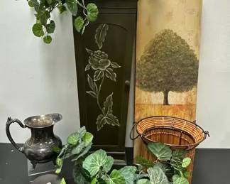 Home Décor – Earthy Green & Brown Charm
Bring warmth & rustic character to your space with this earthy assortment of decorative accents. A perfect mix of natural tones & vintage style!

Includes:

(3) Faux greenery arrangements in tin planters
Vintage MW Rogers silver-plated water pitcher – classic patina & footed base
Vintage pewter creamer pitcher with attached underplate & hinged lid
Wood waste basket – bottom shows wear (see photos)
Decorative candle holder
Green cabinet with floral design & two shelves – 11 1/2" W x 31 3/4" H (shows wear such as scrapes & cracks – see photos)
Wall art – tree design, 12" W x 36" H
Market Insights: Vintage MW Rogers silverplate pitchers often sell in the $20–$40 range depending on condition, while pewter creamers with underplate hold steady interest from traditional décor buyers. The cabinet & wall art add substantial decorative appeal, making this lot a strong value buy for home staging or earthy home styling.
