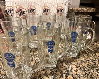 8 Pabst Blue Ribbon mugs and 6 Miller Lite pilsner glasses.
