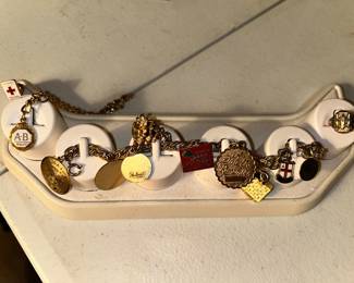 Upper left is a American Red Cross volunteer 10K gold lapel pen. next is a 10K AB Quality bracelet. The charm bracelet has 9 charms:1-14 karat gold Jamaica charm, 1 - 1/20 of 12K GF charm, 3 charms are sterling & the other charms are of a nonvalue metal. The ladies 1956 10K high school Gold Ring on the right.