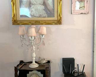 The framed angel art is on this wall, but there is also a pair of smaller tables and a triple lamp.