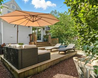 Another view of the cool outdoor furniture including a set consisting of rattan wicker reclining lounge chairs,  coffee table with glass top, and a cozy couch; a large outdoor cantilever offset patio umbrella with steel frame and base