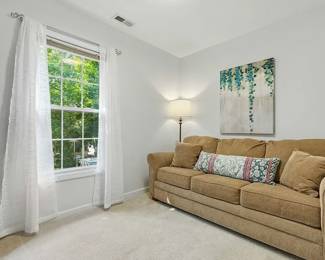 A light brown chenille fabric three seat rolled arm sofa, an electric guitar, botanical theme wall art, standing floor lamp 