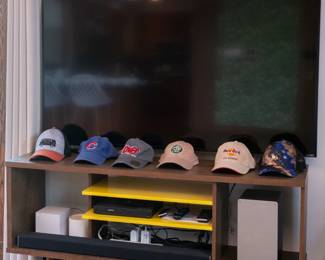 Huge VIZIO flat screen TV, a Deco TP-Link mesh wifi system, Philips DVD player, a collection of baseball caps, 