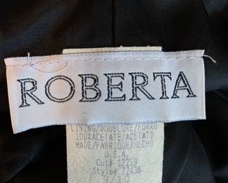 Closeup of the vintage Roberta black formal sheath dress with shoulder straps and lace inserts, size 9/10