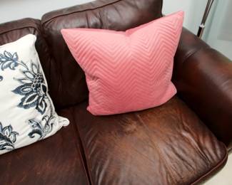 Closeup of the rich deep brown leather three seat rolled arm sofa (with decorative throw cushions!)