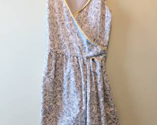 A summery sleeveless wrap dress, white with blue floral pattern and yellow piping