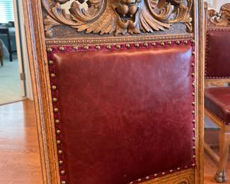 A set of six high-back oak dining room chairs plus one matching arm chair.  7 chairs total   
Chairs have a "Northwind Face" or Lion Face in center, leaf ears, claw feet, upholstered back and seat. Side chairs approx. 42 ½" high; arm chair approx. 45" high. 