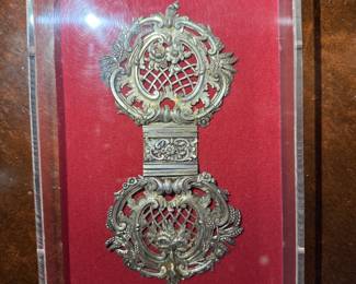 Antique Ornate Silver Filigree Buckle Display
Exquisite antique double buckle featuring intricate silver filigree and lattice design, mounted in a clear display case with red velvet backing. A fine example of 19th-century European metalwork artistry.