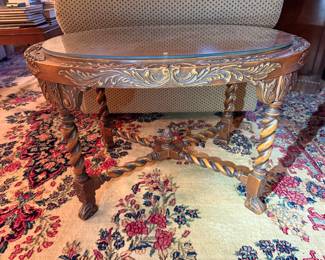Carved oval accent table with ornate floral detailing, barley twist legs, and glass top.