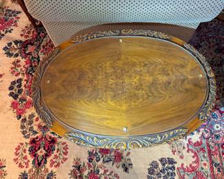 Elegant oval coffee table with rich wood grain, brass gallery trim, and classic mid-century design.