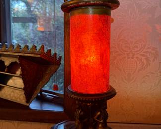 Antique Art Deco Red Glass Cylinder Lamp
Striking early 20th-century lamp with a glowing red crackle-glass cylinder shade and ornate bronze base. Features detailed cherub-style figures and finial top. Excellent statement lighting piece for vintage interiors.