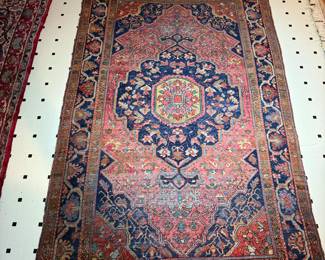 Vintage handwoven Persian rug with intricate medallion and floral motifs in red, blue, and navy tones.