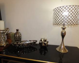 Silver table lamp and silver colored decorative pieces.