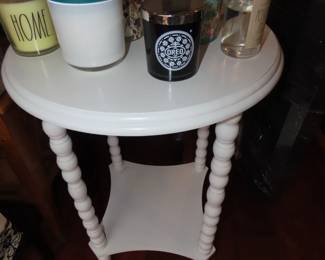 White tall end table filled with candles.