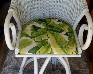white wicker or rattan swivel bar stool with a tropical-themed cushion