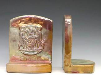 A pair of 20th century Pewabic Pottery bookends. Decorated with a relief Seal of Michigan design and Iridescent glaze in mottled shades of Green, Gold and Purple. Impressed "Pewabic Detroit" marks. Minor surface wear and crazing. 5 1/2" high.