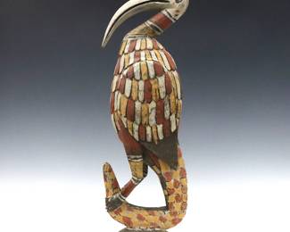 A Papua New Guinea post figure of a Hornbill bird. Carved wooden bird with polychrome decoration and the tail of a crocodile. Some wear, minor damage to base, repaired at neck and bill. 23 3/4" high.