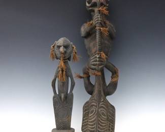 Two Papua New Guinea ceremonial figures. Carved wooden figures with polychrome finish, includes a hanging totem with two inverted zoomorphic figures, inlaid shells and raffia accents, and a standing ancestral figure with raffia decoration. Some wear and shrinkage. Up to 27" high.