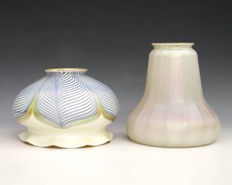Two early 20th century Quezal Art Glass shades. Each with Iridescent White finish, one floriform with Blue and Gold Pulled Feather decoration, the other bell form with ribbed body. Both signed "Quezal" at fitters. Minor surface wear. 3 3/4" and 5 1/4" high with 2 1/4" fitters.