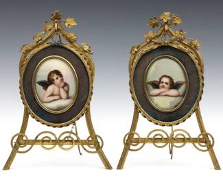 A pair of turn of the century Continental porcelain plaques after Raphael. Each with hand-painted depictions after the Cherubs in "The Sistine Madonna". Presented in cast Brass frames suspended from easels with cast foliate decoration. Slight surface wear, losses to silk mats, one frame lacks cast bow. Plaques are 4" high, 12" high overall.