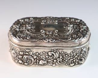 An early 20th century Gorham Sterling jewelry box. Oval hinged box with scrolled floral repousse decoration and velvet lined interior. Impressed maker's mark and "Sterling". 8.18 troy ozs total. Some surface wear, monogrammed. 5 1/2" long.