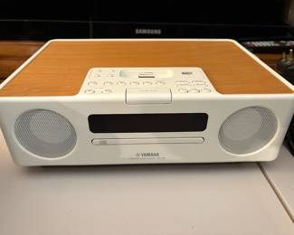 It’s a compact all-in-one audio solution featuring a CD player, FM/AM radio, iPod/iPhone dock (via a compatible adapter), and a clock with alarm functions. The unit has built-in stereo speakers with a wooden top panel for enhanced sound resonance, offering 15W total output (7.5W per channel).
