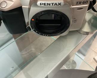 Pentax ZX – 60 is a compact and lightweight. SLR film camera with a black and silver body.