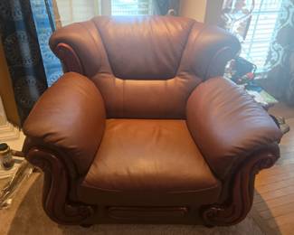 Elegant oversized leather armchair with rich mahogany wood accents and rolled arms. Excellent craftsmanship with plush cushioning for ultimate comfort. Approx. 45” W x 38” H x 38” D