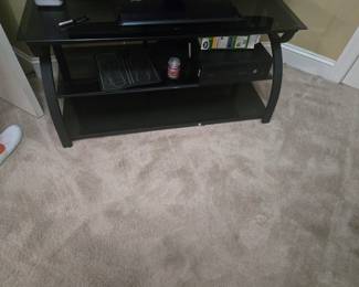 Modern black glass TV stand with metal frame, featuring two lower shelves for storage or media equipment. Clean lines with a contemporary finish.
Approx. 42”W x 18”D x 22”H.