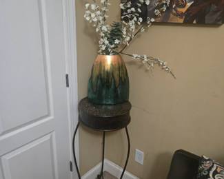 Large ceramic vase with green and gold gradient finish, arranged with white floral stems. Set on an ornate metal pedestal table. Approx. 42” total height.