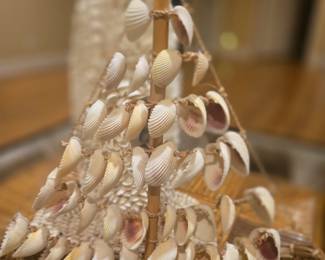 Charming handcrafted sailboat made from woven wicker and adorned with real seashells. Perfect coastal accent piece. Measures about 12” tall.