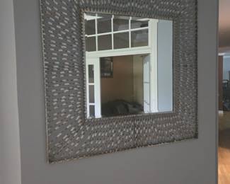 Large square mirror with a unique woven metal-style frame. Eye-catching piece for hallway, living, or dining area.