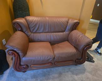 Matching leather loveseat with carved wood detailing and deep, comfortable seating. Beautiful statement piece in excellent condition. Approx. 65” W x 38” H x 38” D.