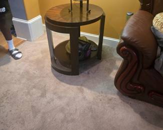 Stylish round side table with a warm wood top and metal frame. Features a lower shelf for storage or décor. Approx. 26” H x 24” D