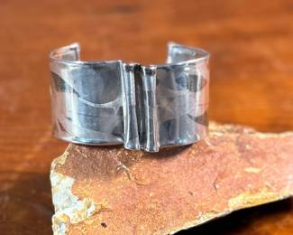 This lot features an artisan made sterling silver cuff, signed by "Cela" as shown in photos with a total approx. weight of 27.33 grams.
