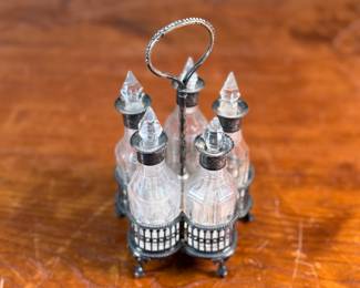 This lot features an antique cruet that appears to be made in the 19th century with five (5) misc. bottles, all of which appear to have silver accents to them. This cruet measures, 7” H x 4” W x 4” D.
