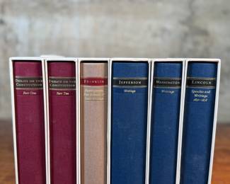 This lot features a collection of six (6) hardcover books with slipcases from the Library of America series. The Library of America is a nonprofit publisher that creates authoritative editions of classic American literature and historical documents. The books in the image include "Debate on the Constitution, " "Franklin: Writings, " "Jefferson: Writings, " "Washington: Writings, " and "Lincoln: Speeches and Writings".
