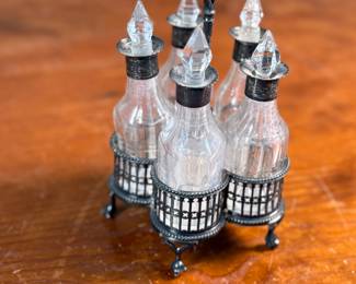 This lot features an antique cruet that appears to be made in the 19th century with five (5) misc. bottles, all of which appear to have silver accents to them. This cruet measures, 7” H x 4” W x 4” D.
