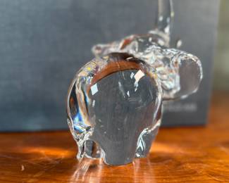 This lot features a Steuben crystal elephant with a raised trunk, designed by James Houston in 1964. Comes with a Steuben box for storage.
