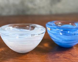 This lot features a set of Kosta Boda Atoll glass votive candle holders, designed by Anna Ehrner, with a white swirl and a blue swirl pattern. Anna Ehrner, born 1948 in Danderyd in Stockholm, is both a designer and glass artist who’s characterized by her simple design language. With an experimental expression, she has an ability to create effectful pieces with only a little color, where lines of color inside the glass has become a recurring feature.
