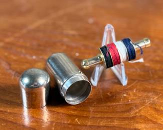 This lot features an antique sterling silver thread holder, manufactured and signed by Napier. The sterling case alone weighs approx. 19.53 grams.
