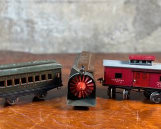 This lot features a collection of three (3) vintage toy train cars, most likely manufactured by Ives Railway Lines. One is marked, “Germany” underneath as shown in photos. All of them appear to be O gauge models.
