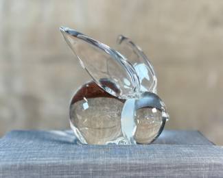 This lot features a collection of three (3) animal themed Steuben Glass sculptures, with five cases to accompany them. Steuben Glass is an American art glass company founded in Corning, New York, in 1903 by Frederick Carder. Originally known for colored glass, it shifted to brilliant clear crystal in the 1930s after being acquired by Corning Glass Works (now Corning Inc.) in 1918. The brand was sold in 2008, production ceased in 2011, and was reacquired by Corning Inc., which now oversees its production and sales through the Corning Museum of Glass.
