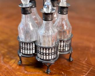 This lot features an antique cruet that appears to be made in the 19th century with five (5) misc. bottles, all of which appear to have silver accents to them. This cruet measures, 7” H x 4” W x 4” D.

