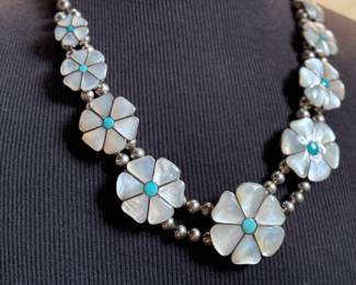This lot features a vintage Zuni Native American squash blossom necklace, made of sterling silver with mother-of-pearl and turquoise inlay with a floral design. This necklace measures 24” and has a total approx. weight of 134.87 grams.
